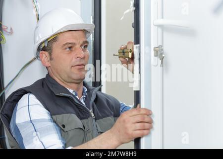 man changing a door lock of the entrance door Stock Photo