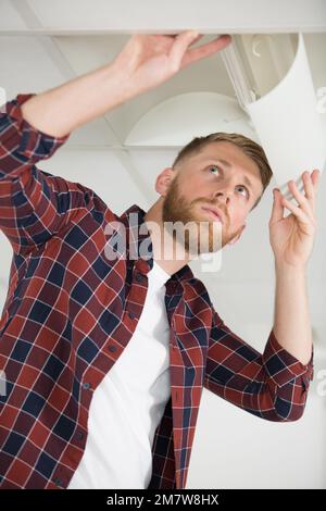 man changing light bulb in lamp indoors Stock Photo