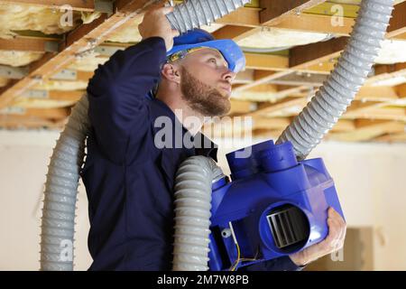 a plumber checking ceiling pipes Stock Photo