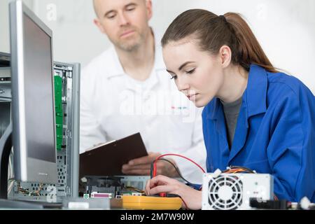 Young woman using multimeter on computer components Stock Photo