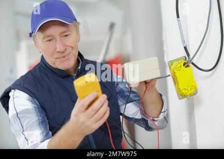 experienced electrician doing electrical work Stock Photo