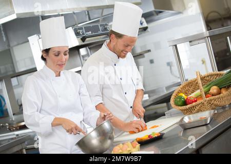 male and female chefs working together in professional kitchen Stock Photo