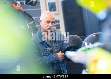 elderly man choosing helmet in store Stock Photo