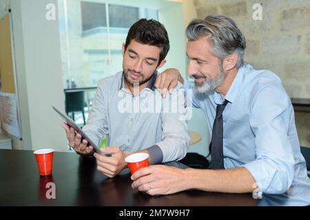 friendly businessmen looking at tablet while on break Stock Photo