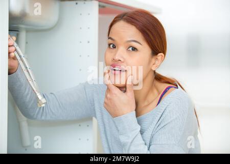 woman holding tubes under the sink Stock Photo