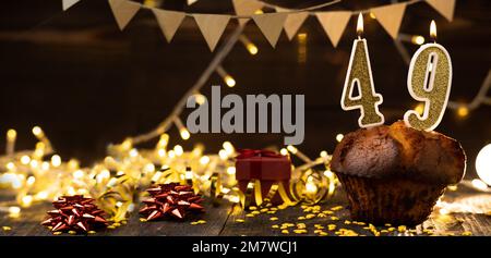 Number 49 golden festive burning candles in a cake, wooden holiday background. forty-nine years from the date of birth. the concept of celebrating a b Stock Photo