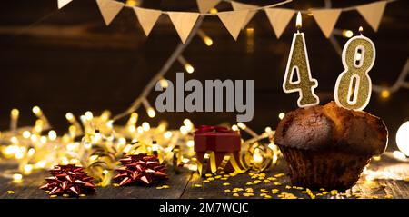 Number 48 golden festive burning candles in a cake, wooden holiday background. forty eight years from the date of birth. the concept of celebrating a Stock Photo