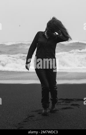 Traveler walking along on Reynisfjara beach monochrome scenic photography Stock Photo