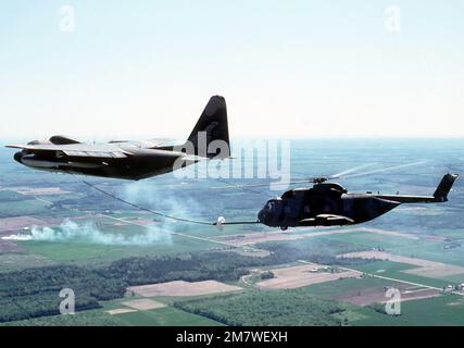 A left side view of an HC-130 Hercules aircraft refueling an HH-3E Jolly Green Giant helicopter, in flight, during a reserve rescue exercise. Base: Phelps Collins Ang Base State: Michigan (MI) Country: United States Of America (USA) Stock Photo