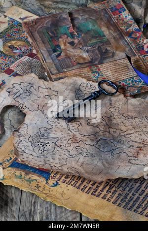 old black key laying on a spread of ancient papers, maps and illuminated texts. mystery book cover style. Stock Photo