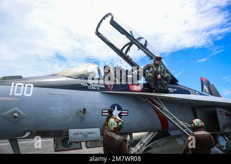 PHILIPPINE SEA (May 12, 2022) Lt. Cmdr. Michael Andrews, top right, assigned to the 'Black Aces' of Strike Fighter Squadron (VFA) 41, prepares to exit an F/A-18F Super Hornet on the flight deck of the Nimitz-class aircraft carrier USS Abraham Lincoln (CVN 72). Abraham Lincoln Strike Group is on a scheduled deployment in the U.S. 7th Fleet area of operations to enhance interoperability through alliances and partnerships while serving as a ready-response force in support of a free and open Indo-Pacific region. Stock Photo