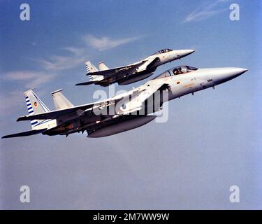 A right side air-to-air view of two F-15 Eagle aircraft. The aircraft are armed with AIM-9 Sidewinder mounted on the wing pylons and AIM-7 Sparrow missiles. Country: Unknown Stock Photo