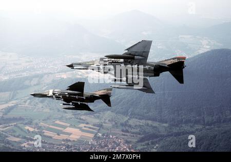 A air-to-air left side view of two F-4E Phantom II aircraft banking to the right. The aircraft, assigned to the 526th Tactical Fighter Squadron, 86th Tactical Fighter Wing, are each carrying four AIM-7 Sparrow missiles and four AIM-9 Sidewinder missiles. Country: Deutschland / Germany (DEU) Stock Photo