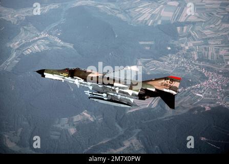 An air-to-air left side view of an F-4E Phantom II aircraft banking to the right. The aircraft, from the 526th Tactical Fighter Squadron, 86th Tactical Fighter Wing, is carrying four AIM-7 Sidewinder missiles. Country: Deutschland / Germany (DEU) Stock Photo