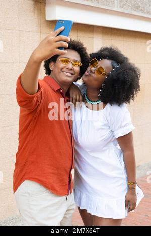 Couple with afro hair taking selfies in the city street Stock Photo