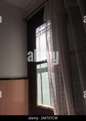 Morning Light Through Sheer Curtain on Old Window in Dim Room Stock Photo