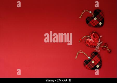 Three heart shapes made of cloth on a red background Stock Photo