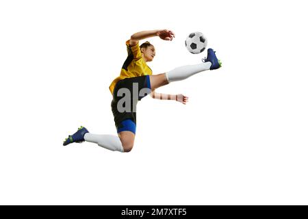 Kicking ball in a jump. Young professional female football, soccer player in motion, training, playing isolated over white background Stock Photo