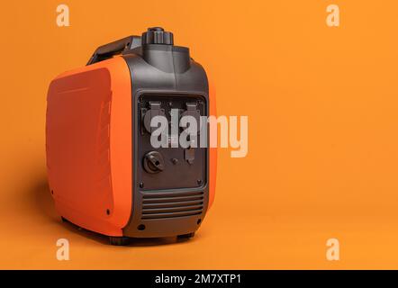 Inverter gasoline generator on an orange background. Stock Photo