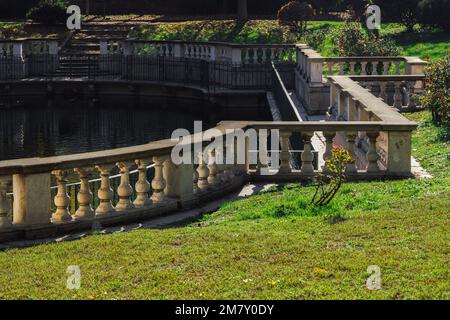 An artificial pond at a city park with grass on the Guastalla Gardens in Milan, Italy during the fall season. Stock Photo