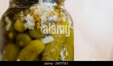 Blurred image of canned cucumbers in glass jar close-up on blurred light background Stock Photo