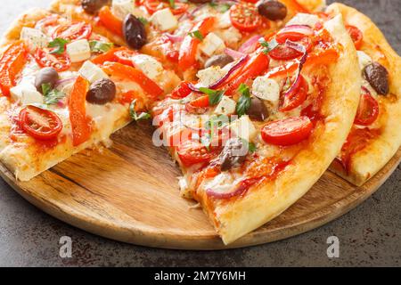 Sliced Greek pizza with olive, tomato, Mozzarella and feta cheese, onions, pepper on wooden board. Horizontal Stock Photo