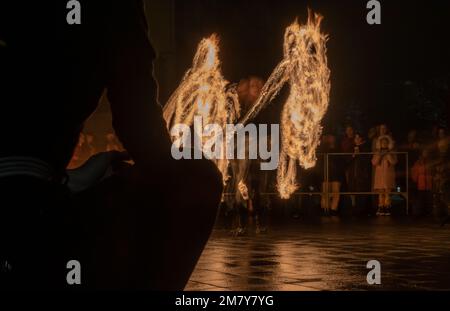 Blurred silhouettes of people and burning fire on dark night background of city square. Ukraine, Zhytomyr, November 22, 2022 Stock Photo