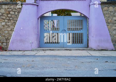 A gray metallic door with purple wall in a Moroccan street Stock Photo