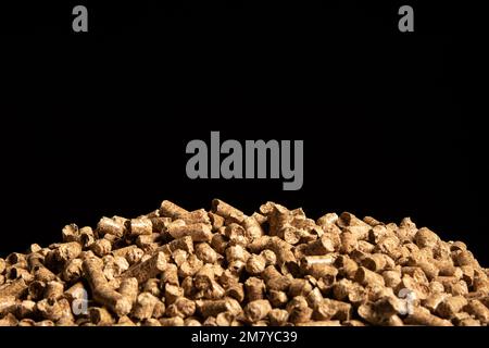 Many small compressed wooden sawdust of cylindrical shape are arranged in a heap on a black background. Cats toilet Stock Photo