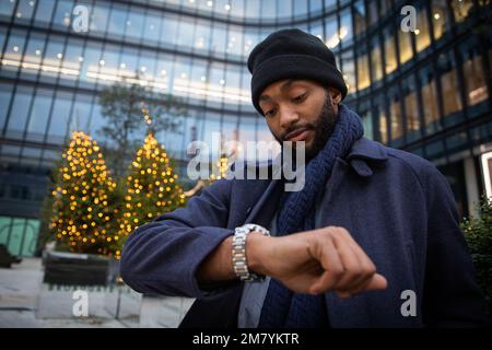 African businessman checks the time from his watch on a winter day Stock Photo