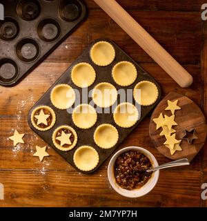 Flat lay of metal bun tin containing uncooked pastry ready for making star topped mince pies. Christmas baking. Stock Photo