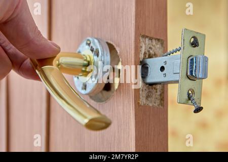 Door handle with latch at time of installation on internal wooden door. Stock Photo