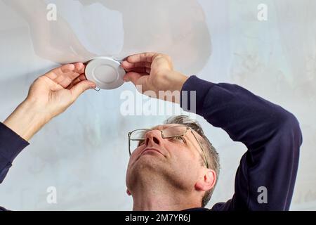 Installation of spot LED lamp with clasp in stretch ceiling. Stock Photo