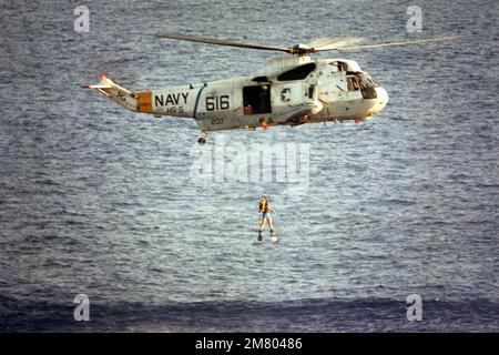 A search and rescue diver jumps from a hovering SH-3H Sea King helicopter of Helicopter Anti-submarine Squadron 5 (HS-5) during a drill. Country: Mediterranean Sea (MED) Stock Photo