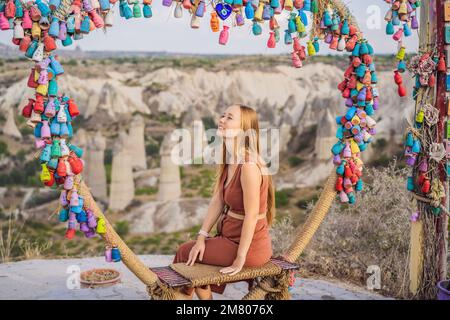 Young woman exploring valley with rock formations and fairy caves near Goreme in Cappadocia Turkey. Wish tree. Small multi-colored jugs with Stock Photo