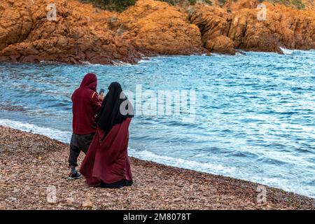 MUSLIM COUPLE IN THE CALANQUE DU PETIT CANEIRET INLET, THE RED ROCKS OF THE MASSIF DE L'ESTEREL, SAINT-RAPHAEL, VAR, FRANCE Stock Photo