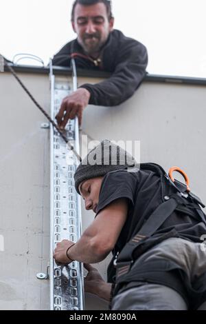 team of electrical engineers install the electrical cables for the autonomous photovoltaic solar panel system. It is installed on a scale and uses a m Stock Photo