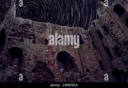 Norham Castle in ruins with night sky and star trails Stock Photo