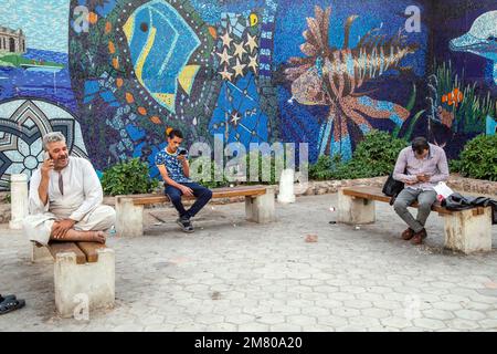 MEN WITH THEIR CELL PHONES IN FRONT OF THE ENTRANCE TO THE MOSAIC-COVERED SOUK, EL DAHAR MARKET, POPULAR QUARTER IN THE OLD CITY, HURGHADA, EGYPT, AFRICA Stock Photo