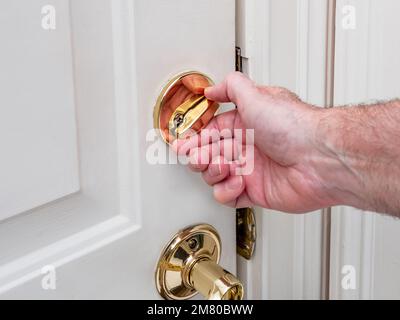 Man locking deadbolt door lock on white entry door. Home security burglar and robbery prevention. Stock Photo