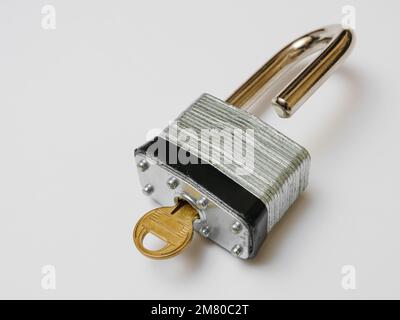Unlocked padlock with key on white background. Stock Photo