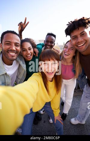 Multiethnic group of friends taking a selfie outdoors, having fun in sunny day. Stock Photo