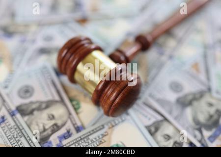 Wooden judge gavel on dollar bills background, shallow focus. Stock Photo