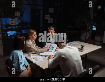 Business discussion in contemporary evening office of team Stock Photo