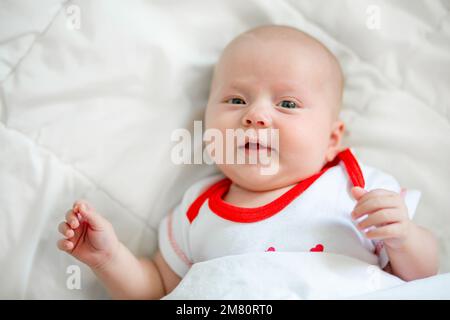 The little baby sleeps folding its legs one on top of the other. Small pink heels of a newborn baby dressed in a diaper. Stock Photo