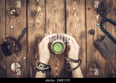 A fortune teller or an oracle with objects for divination holds an extinguished candle during the session. Psychic readings and clairvoyance concept. Stock Photo