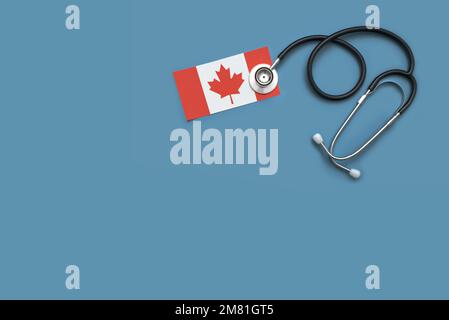 Overhead flat lay of a doctor's stethoscope with the Canadian flag against a blue background Stock Photo