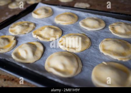 Raw puff pastry dumplings on a oven tray. Close up Stock Photo