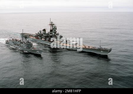 An elevated starboard bow view of the battleship USS IOWA (BB-61) refueling the guided missile destroyer USS HALYBURTON (FFG-40) during an underway replenishment. The ships are participating in NATO Exercise Ocean Safari '85. Subject Operation/Series: OCEAN SAFARI '85 Country: Atlantic Ocean (AOC) Stock Photo