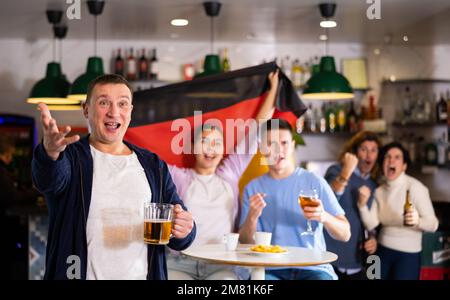 Enthusiastic German fans scream with joy in beer bar. Germany victory Stock Photo
